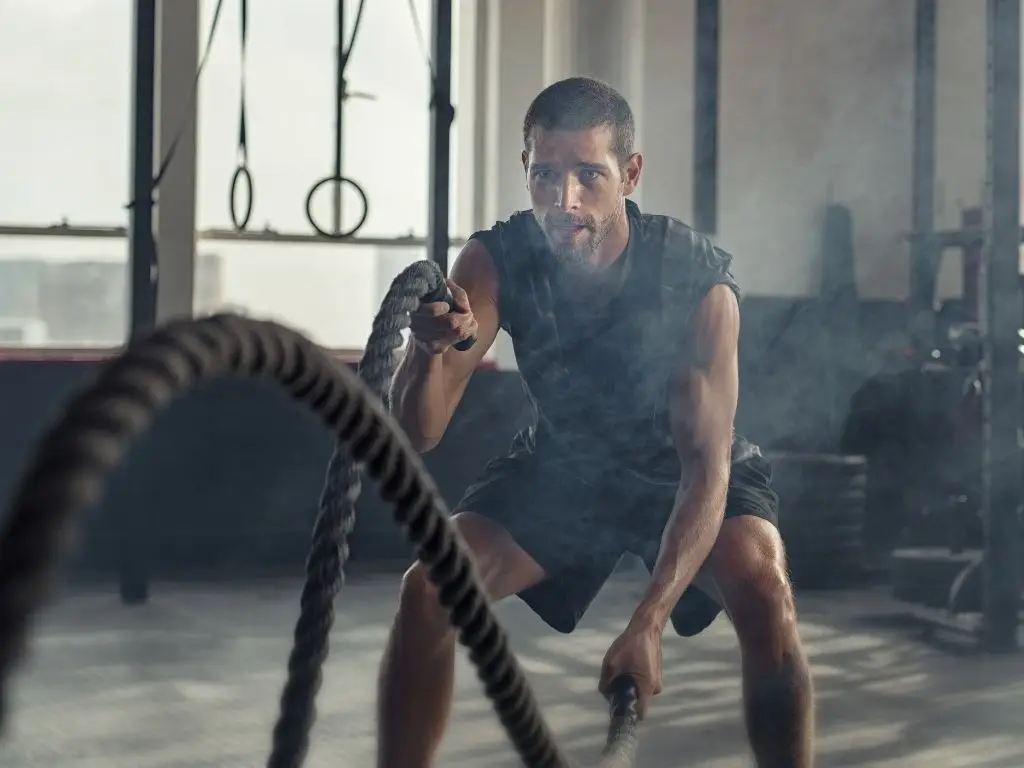 Homme à l’entraînement avec des cordes ondulatoires, en salle de sport