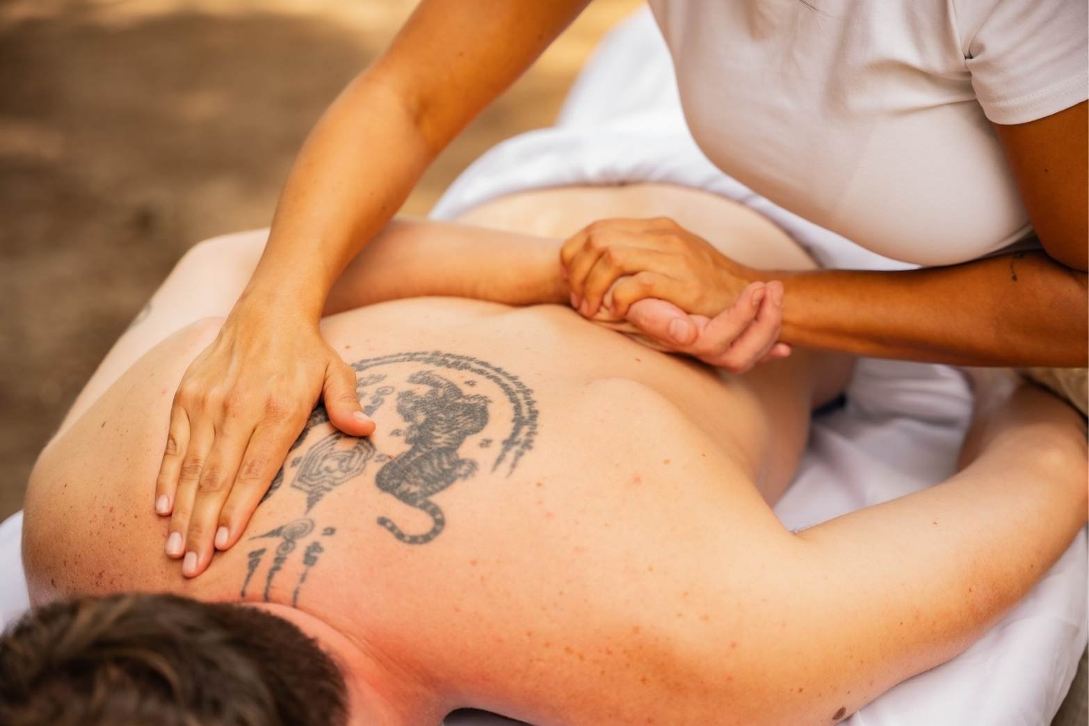 Massage du dos sur une table drapée de blanc, à Nice