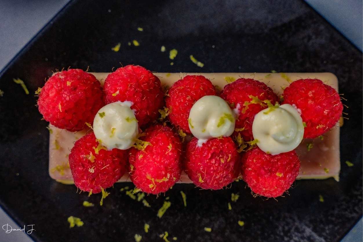 Dessert aux framboises dressé sur une assiette noire, à Nice